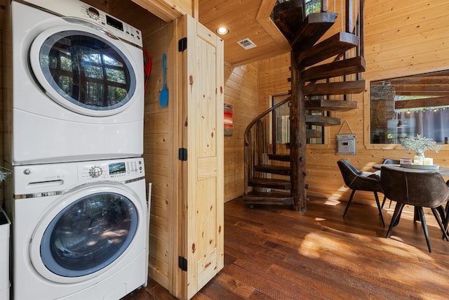 laundry area featuring wood walls, dark wood-type flooring, stacked washer / drying machine, and wooden ceiling