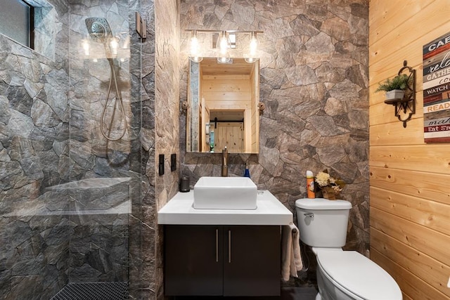 bathroom with wooden walls, toilet, vanity, and walk in shower