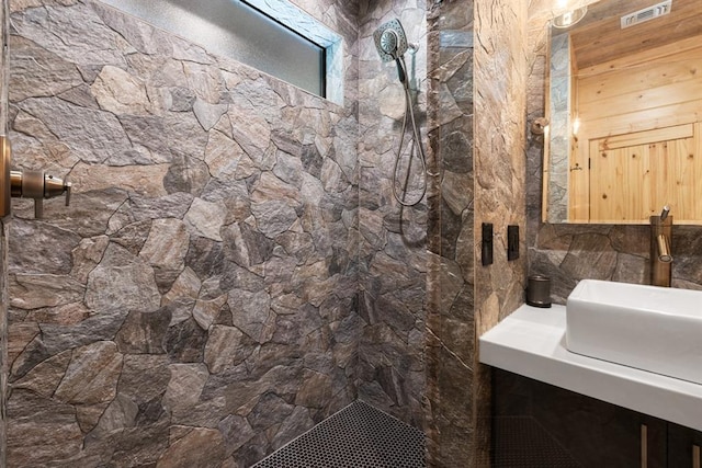 bathroom with tiled shower and vanity