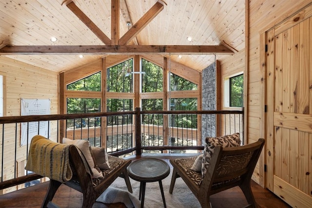 living area featuring lofted ceiling with beams, wood walls, and plenty of natural light