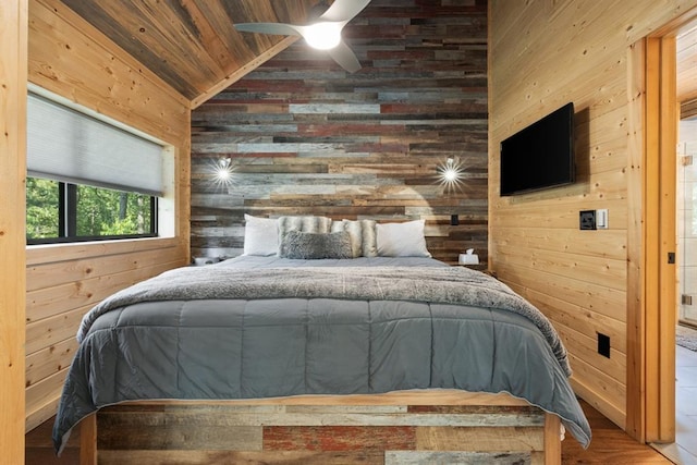 bedroom with hardwood / wood-style floors, ceiling fan, lofted ceiling, and wooden walls