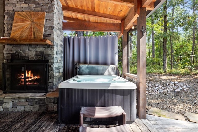 wooden terrace with an outdoor stone fireplace, central AC, and a hot tub