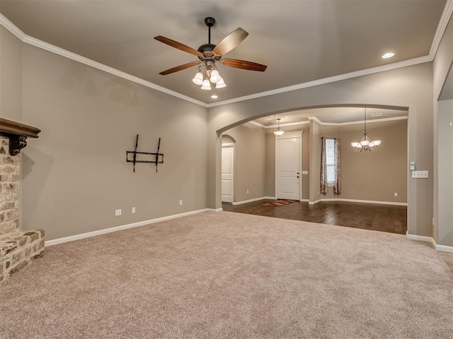 unfurnished living room featuring ceiling fan with notable chandelier, dark carpet, and ornamental molding