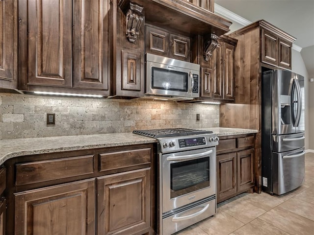 kitchen featuring crown molding, decorative backsplash, appliances with stainless steel finishes, light tile patterned flooring, and dark brown cabinetry