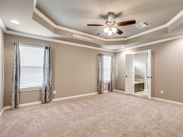 empty room with ornamental molding, a raised ceiling, and a healthy amount of sunlight