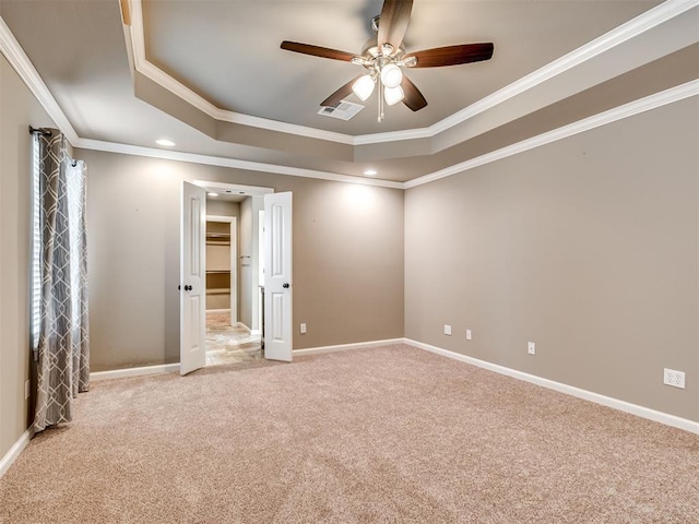 spare room with a tray ceiling, ceiling fan, ornamental molding, and light colored carpet