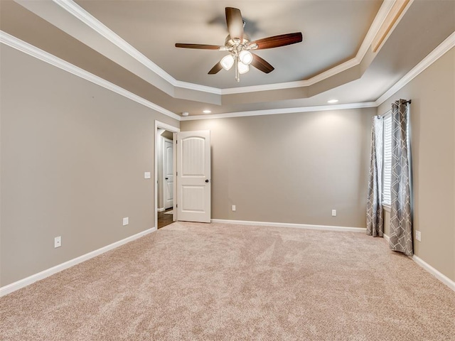 carpeted spare room featuring a raised ceiling, ceiling fan, and crown molding