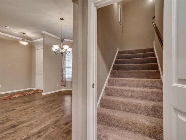 stairs with hardwood / wood-style floors, an inviting chandelier, and ornamental molding