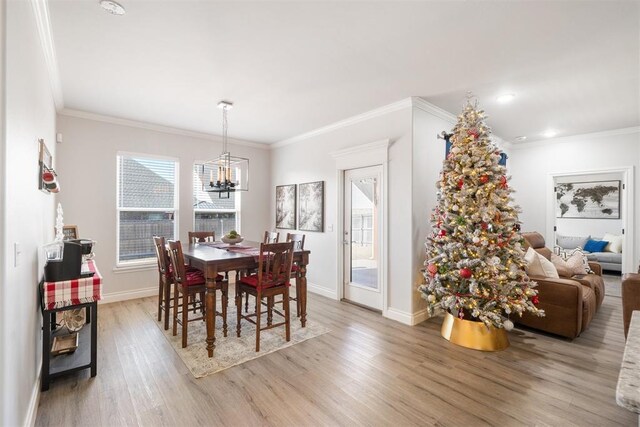 dining space with a notable chandelier, crown molding, and light hardwood / wood-style flooring