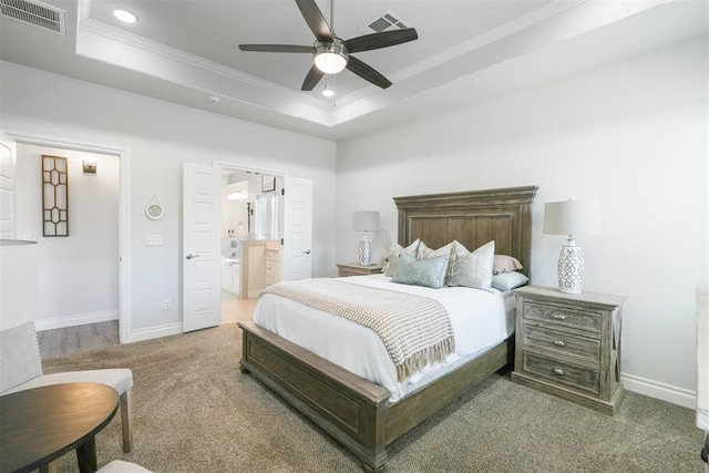 bedroom featuring carpet, ensuite bath, ceiling fan, ornamental molding, and a tray ceiling