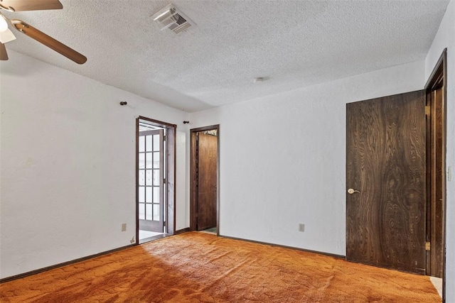 empty room featuring a textured ceiling, light colored carpet, and ceiling fan