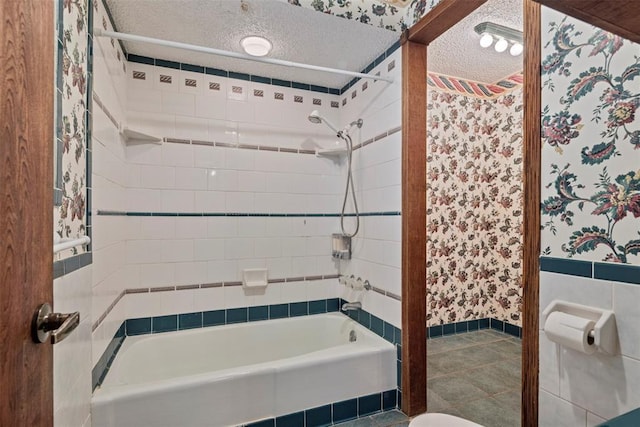 bathroom featuring a textured ceiling and tiled shower / bath