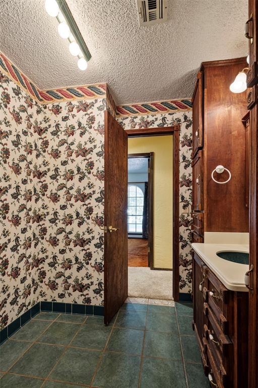 bathroom with tile patterned flooring, vanity, track lighting, and a textured ceiling