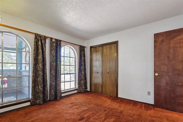 unfurnished bedroom featuring carpet floors, a textured ceiling, and a closet