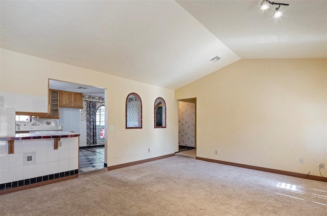 unfurnished living room with light colored carpet and vaulted ceiling