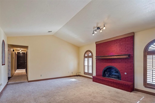 unfurnished living room featuring a fireplace, light colored carpet, and lofted ceiling