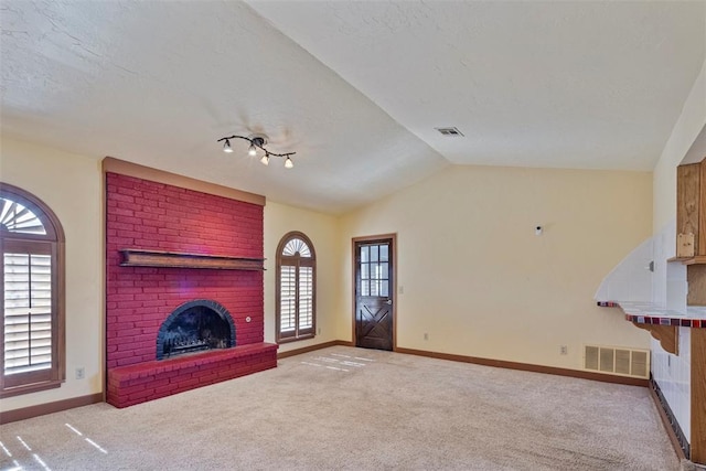 unfurnished living room featuring a textured ceiling, lofted ceiling, a fireplace, and light carpet