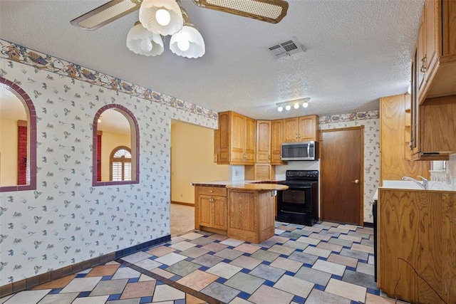 kitchen with ceiling fan, sink, black electric range, a textured ceiling, and a kitchen island