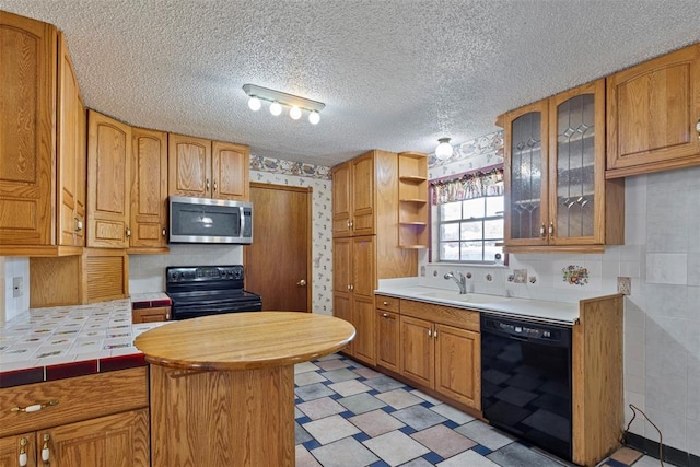 kitchen with black appliances, tile counters, sink, and a textured ceiling