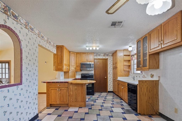 kitchen featuring black appliances, sink, a textured ceiling, and tile countertops