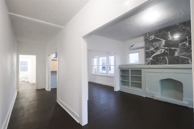 hall featuring a wall unit AC, dark wood-type flooring, and a textured ceiling