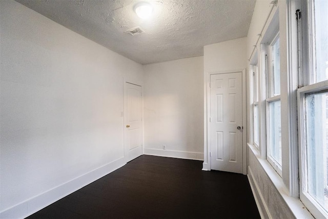 empty room featuring dark hardwood / wood-style flooring and a textured ceiling