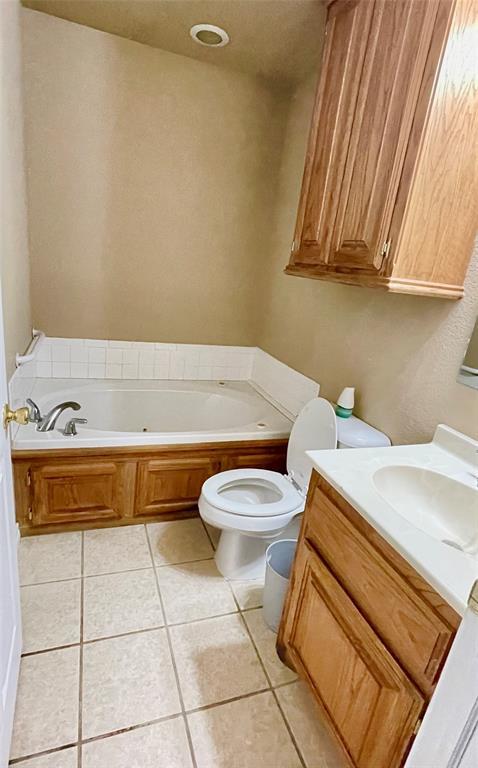 bathroom with tile patterned floors, a washtub, toilet, and vanity