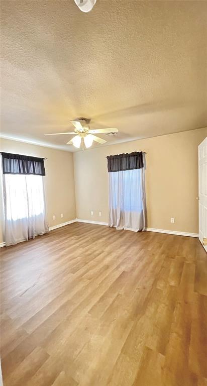 empty room with a textured ceiling, hardwood / wood-style flooring, and ceiling fan