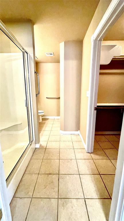 bathroom featuring tile patterned flooring, toilet, and an enclosed shower