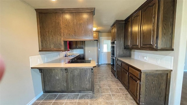 kitchen featuring dark brown cabinetry, sink, tasteful backsplash, tile patterned flooring, and appliances with stainless steel finishes