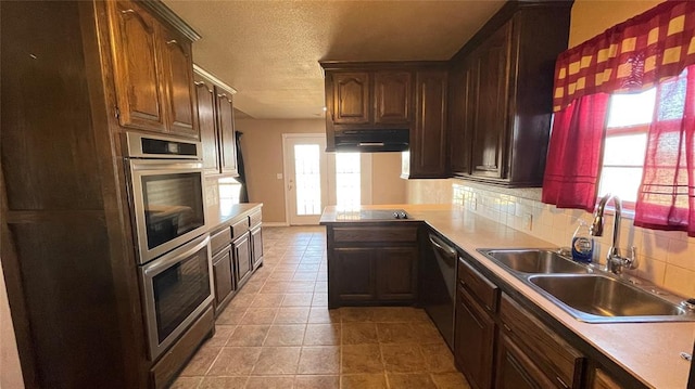 kitchen featuring backsplash, sink, a textured ceiling, kitchen peninsula, and stainless steel appliances