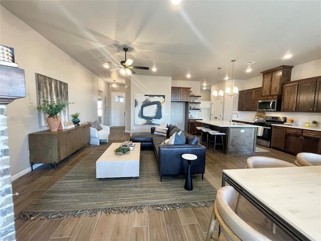 living room featuring a ceiling fan, wood tiled floor, and baseboards