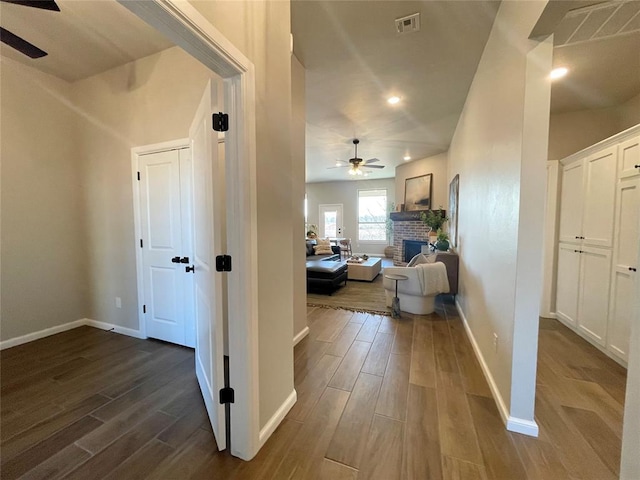 hall featuring baseboards, visible vents, and wood finish floors