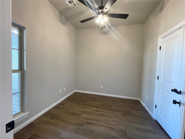 empty room with dark wood-style floors, visible vents, ceiling fan, and baseboards