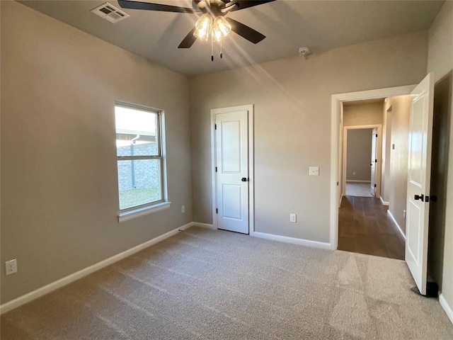 unfurnished bedroom with a ceiling fan, carpet flooring, visible vents, and baseboards