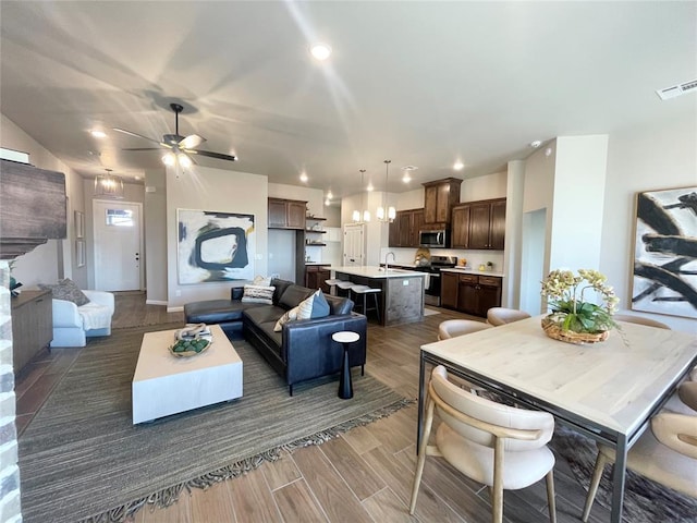 living room featuring ceiling fan, sink, and dark hardwood / wood-style floors