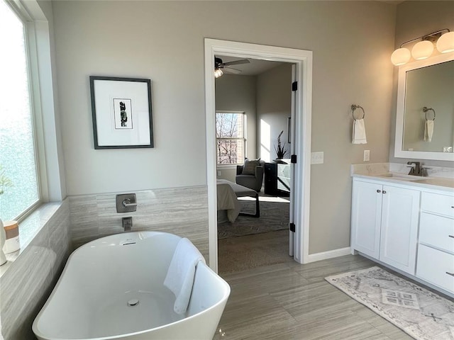 bathroom with vanity, a healthy amount of sunlight, a bath, and tile walls