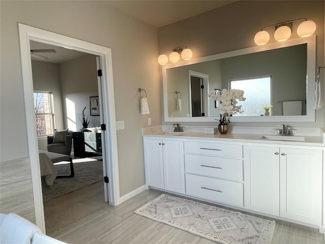 bathroom featuring baseboards, double vanity, a sink, and connected bathroom