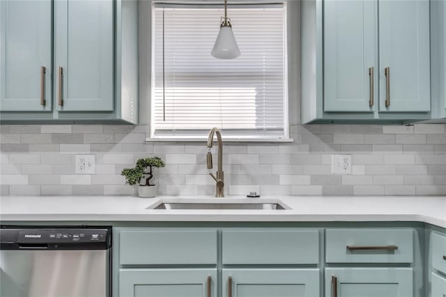 kitchen with decorative backsplash, pendant lighting, stainless steel dishwasher, and sink