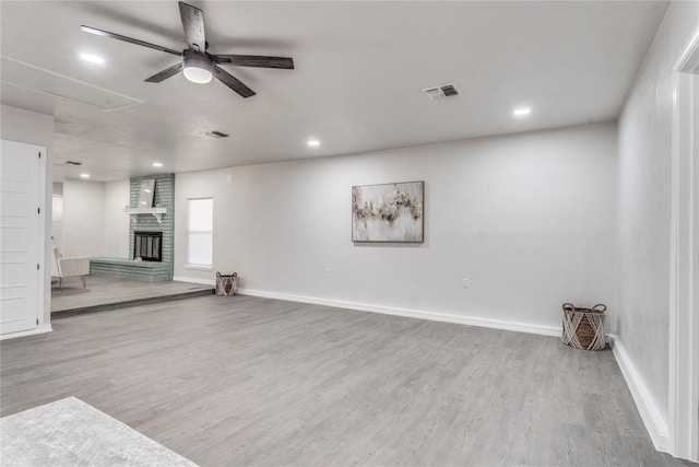 unfurnished living room featuring hardwood / wood-style floors, ceiling fan, and a brick fireplace