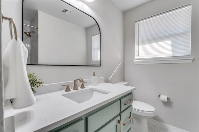 bathroom with vanity, toilet, and a tile shower