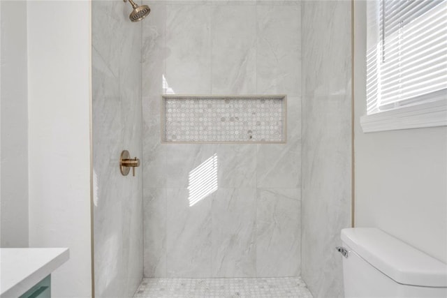 bathroom with vanity, toilet, and tiled shower