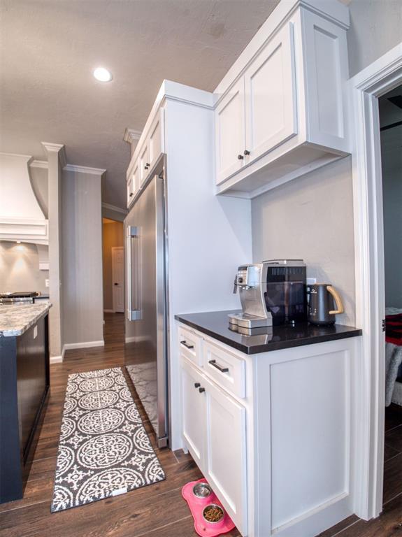 kitchen featuring white cabinetry, dark hardwood / wood-style floors, premium range hood, stainless steel built in fridge, and ornamental molding