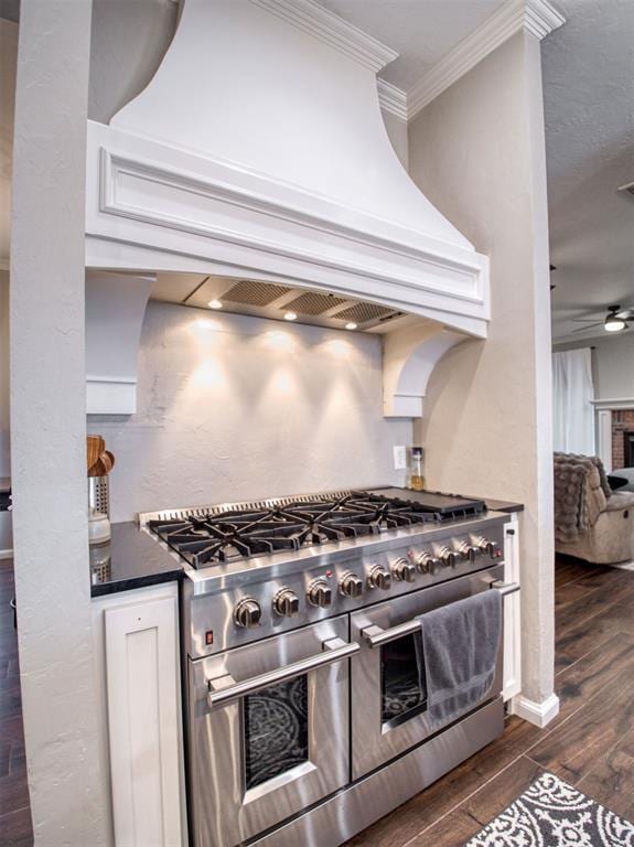 kitchen with premium range hood, a brick fireplace, ceiling fan, crown molding, and double oven range