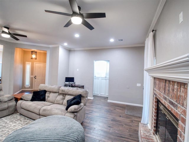 living room featuring ceiling fan, dark hardwood / wood-style flooring, crown molding, and a brick fireplace