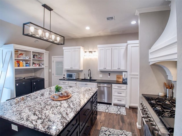 kitchen featuring appliances with stainless steel finishes, a kitchen island, sink, independent washer and dryer, and white cabinetry