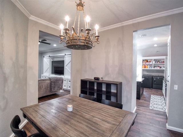 dining space featuring a barn door, crown molding, dark wood-type flooring, and ceiling fan with notable chandelier