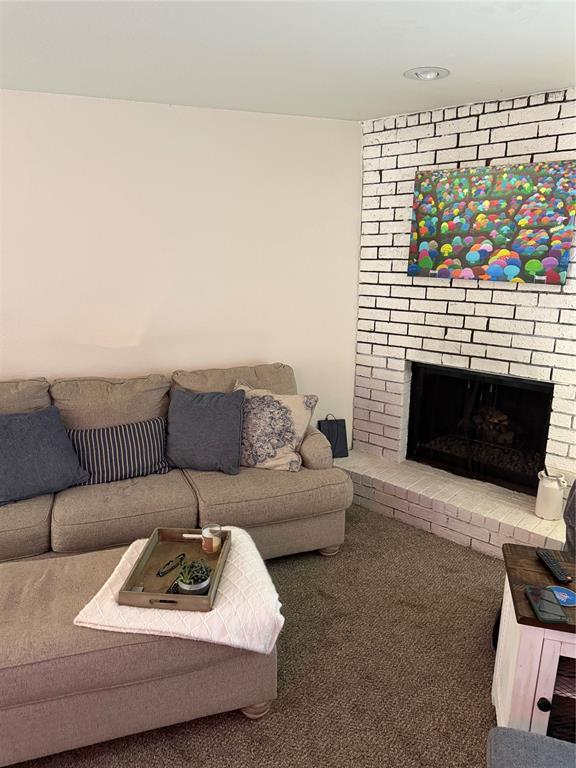 carpeted living room with a brick fireplace