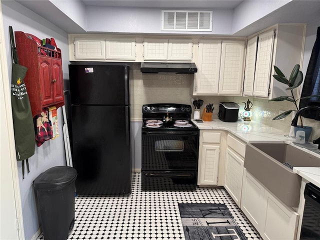 kitchen featuring under cabinet range hood, a sink, visible vents, light countertops, and black appliances