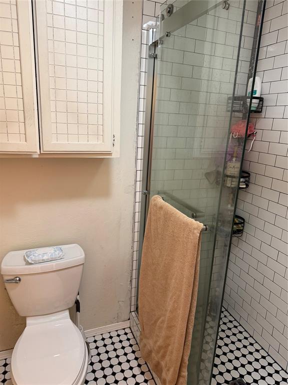 bathroom with a stall shower, toilet, and baseboards